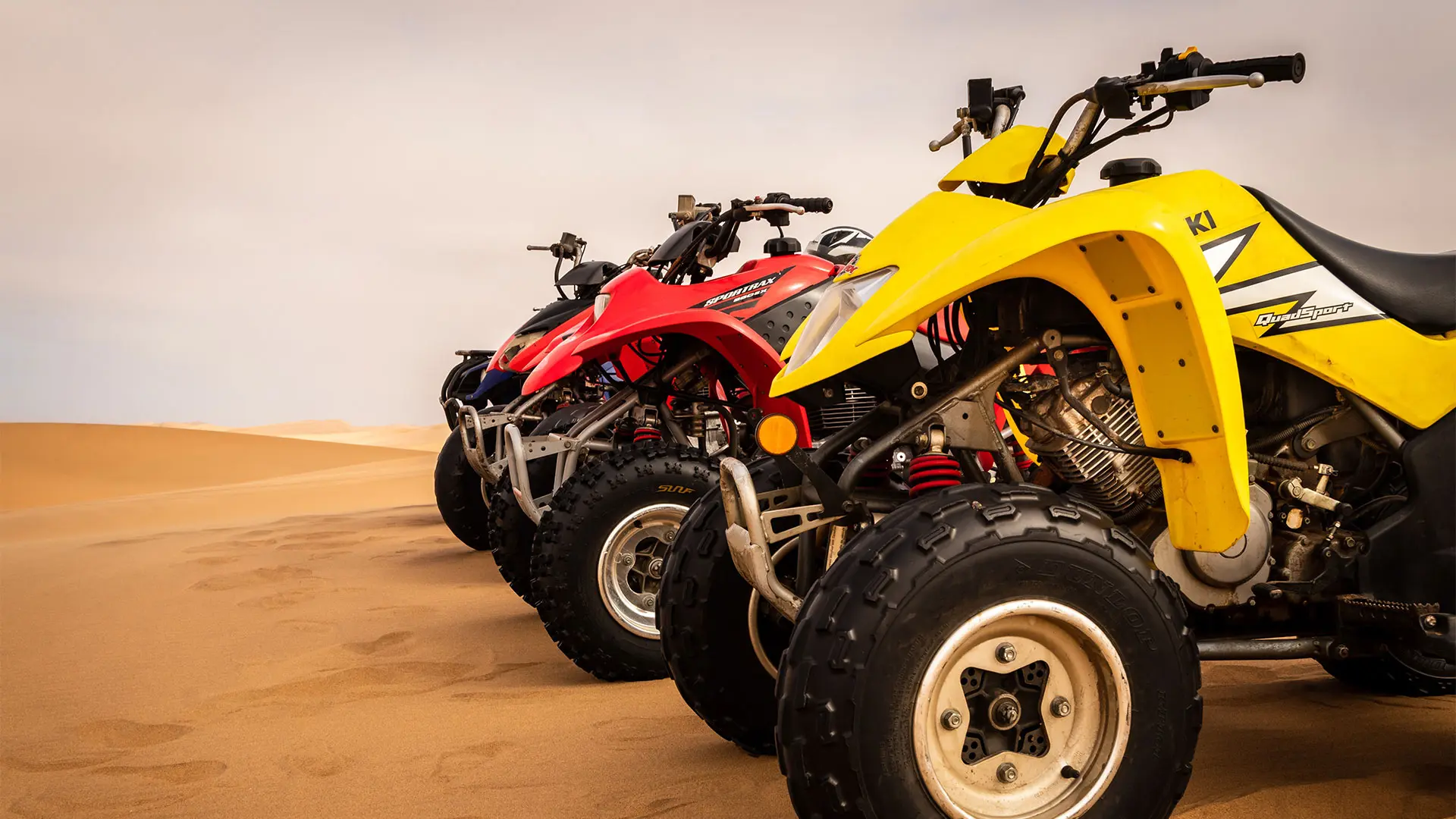 Side view of modern multi-colored all-terrain vehicles stand in the desert