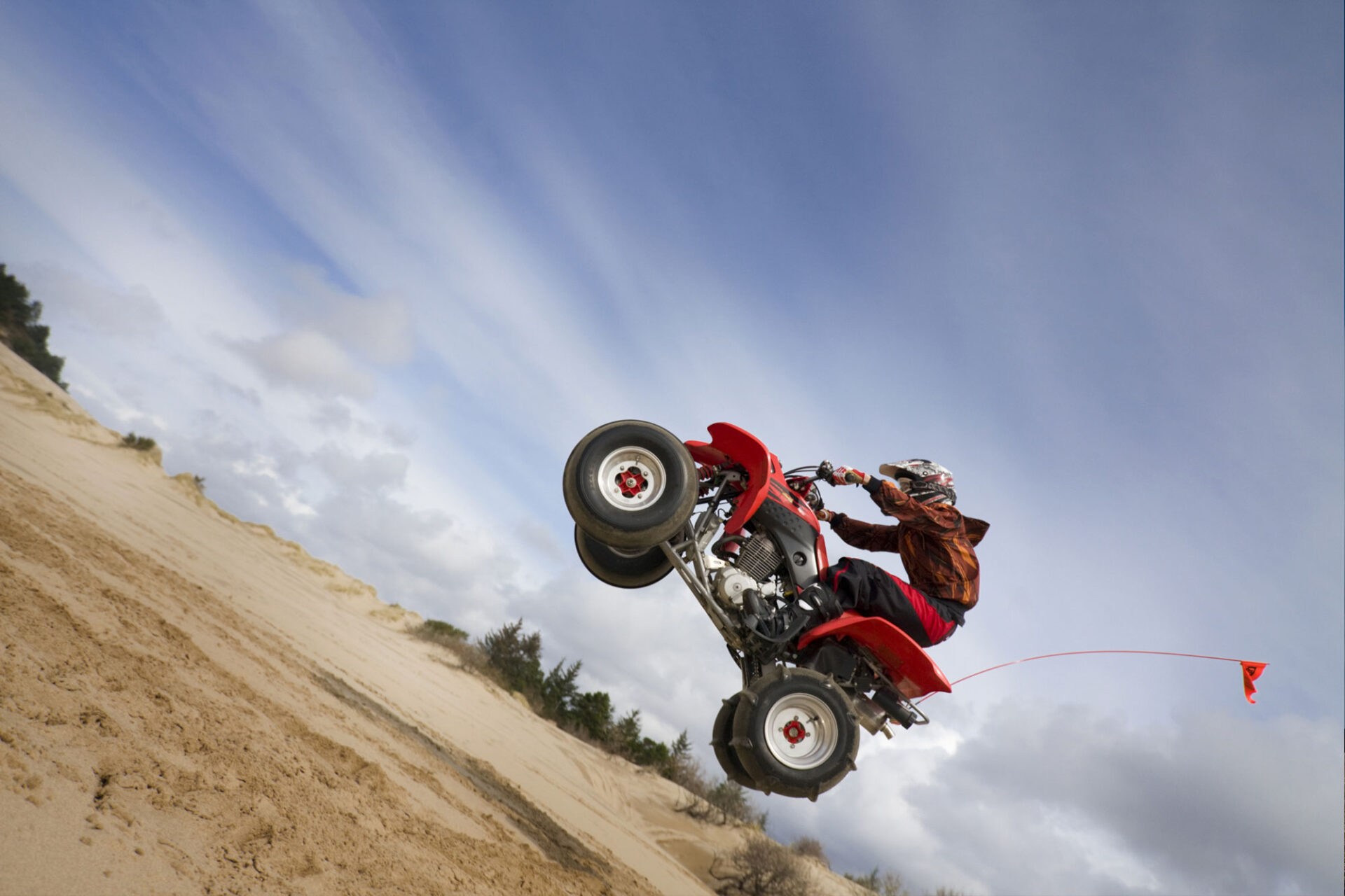 Angled shot of a teen jumping his ATV in the oregon dunes